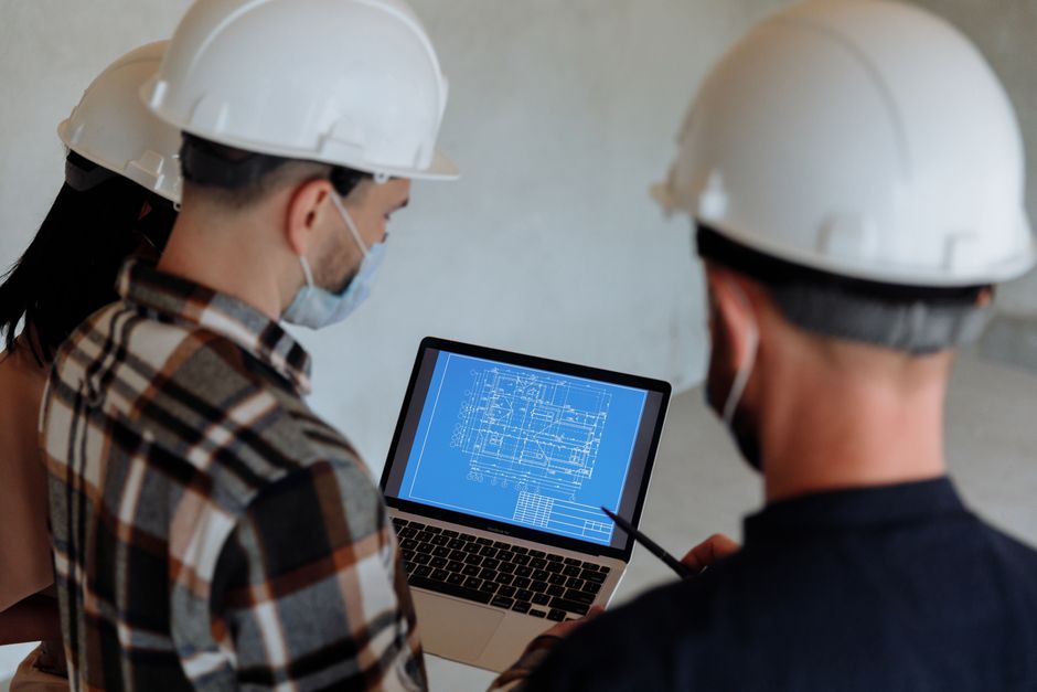 Engineers reviewing a blueprint on a laptop