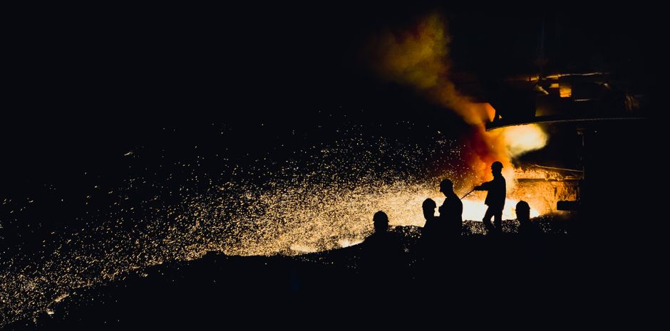 Foundry workers silhouetted against fiery sparks
