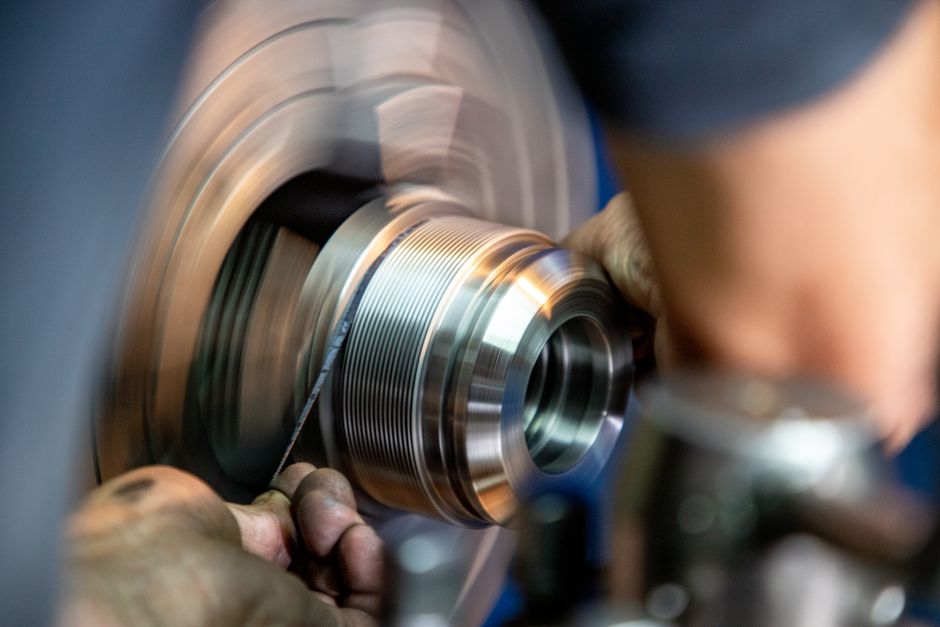 Worker precision grinding a metal component