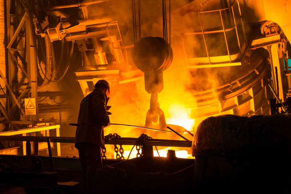 Worker operating machinery with molten metal and intense flames